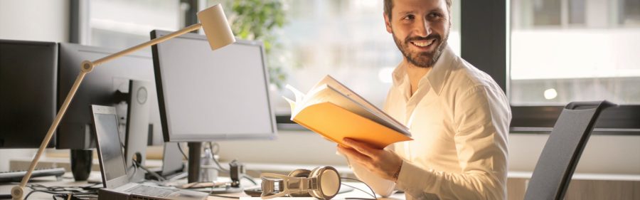 Man smiling while reviewing notes at his desk