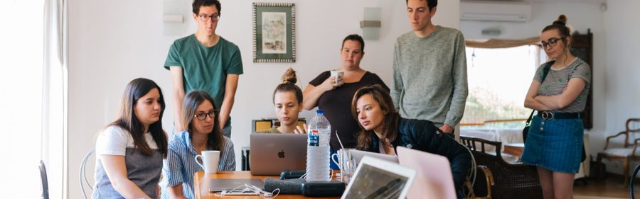 Group of colleagues gathered around a laptop discussing a project