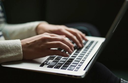Close-up of hands typing a job application on a laptop